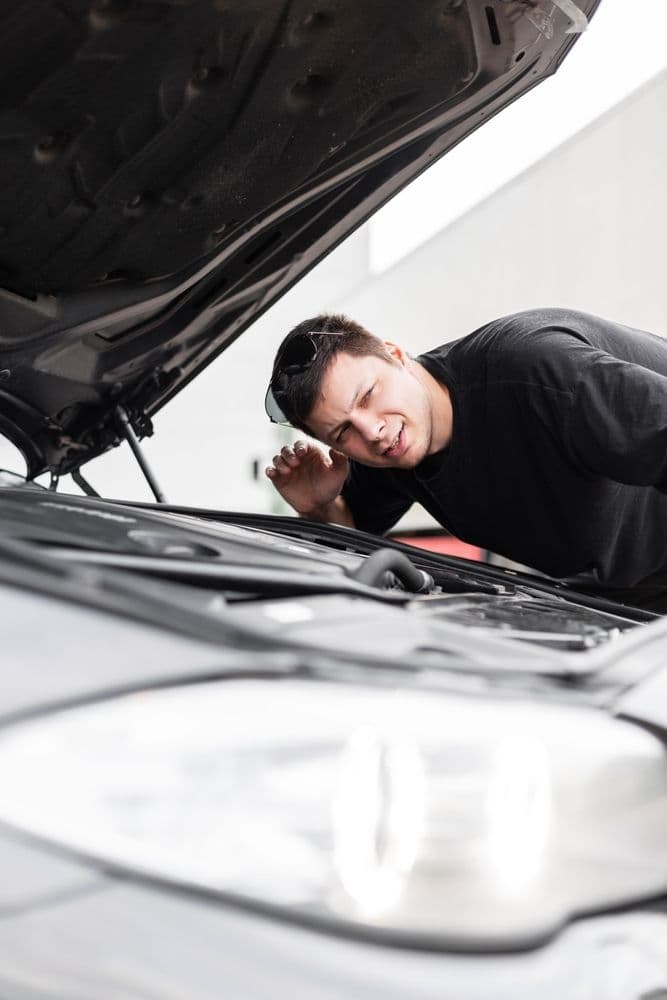 Man driver stands the car with the hood open and checks the sound of the engine